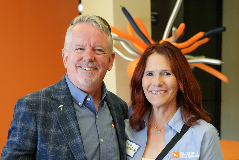 Attendees greet one another during a UTEP Engineering homecoming gathering, with two individuals shaking hands while conversing in a banquet-style event space where additional attendees and name badges are visible in the background.